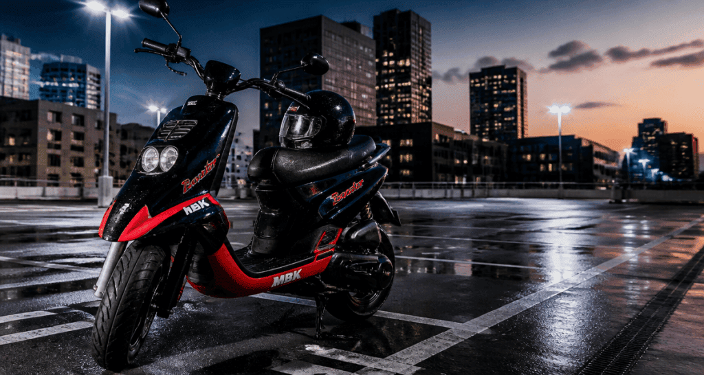 scooter booster 50cc noir rouge sur parking urbain