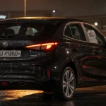 Avis mg3 hybride : arrière-3/4 sur parking urbain mouillé, citadine hybride 195 ch