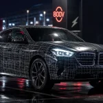 BMW iX4 prototype camouflé sur parking humide